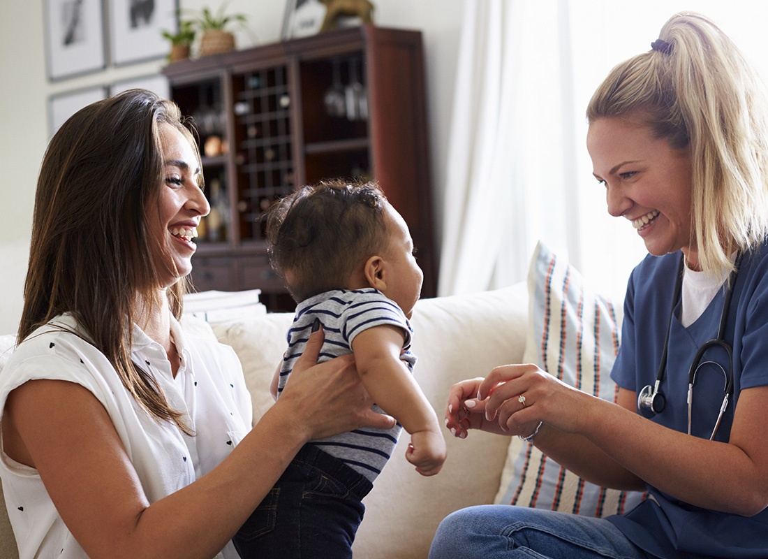 Home Health Care Business Insurance - A Health Professional Visits With a Young Mother and Her Child and Records the Patient’s Health Information While Sitting on the Sofa