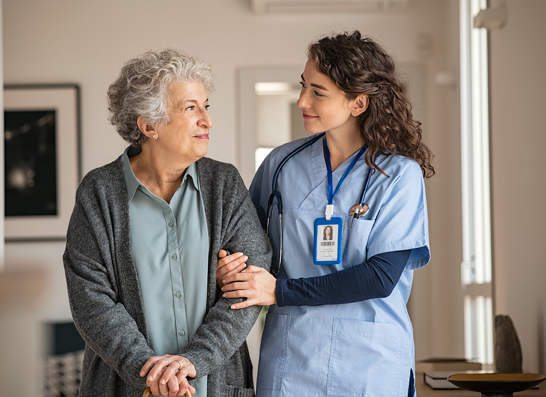 Medicare - Health Care Worker Assisting a Senior by Holding Her Arm