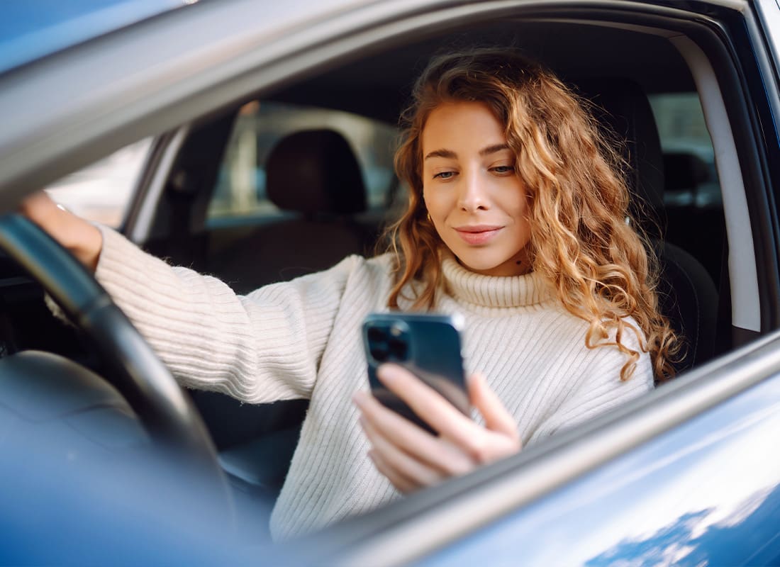 Read Our Reviews - Young Woman Looking at Her Phone While Sitting in Her Car
